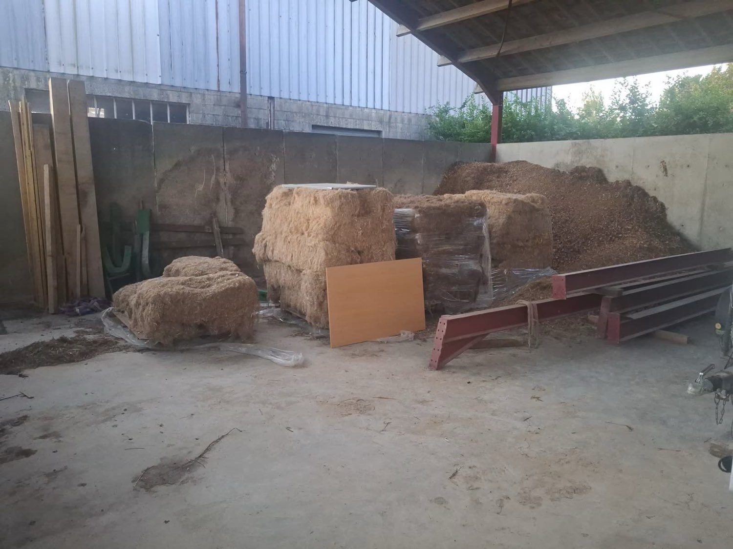 Hangar agricole où attendent du bois, des plaquettes forestières et du fourrage avant leur passage au séchage